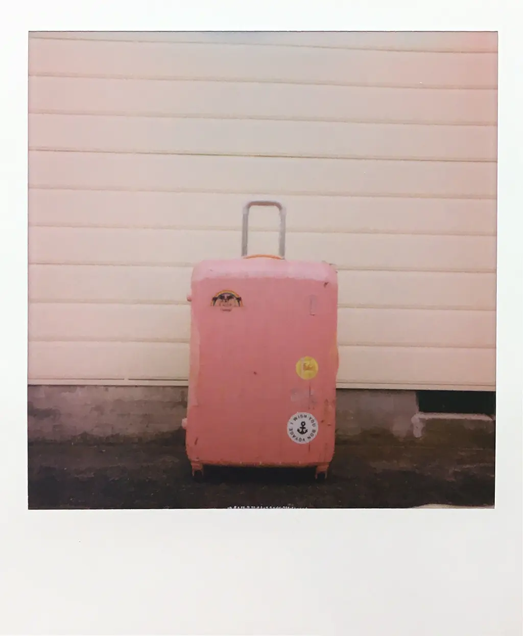 Polaroid avec une valise rose de voyage pour la FAQ Communication et Webmarketing
